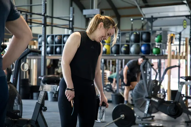 Lachend lid komt op adem met springtouw en bidon na een Competition METCON