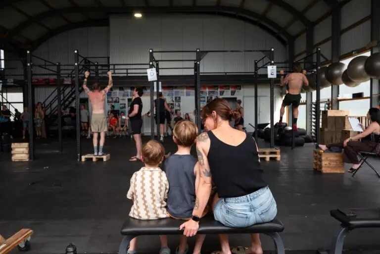 Kinderen kijken vanaf de bank toe bij de rig in de box van CrossFit Waalfront