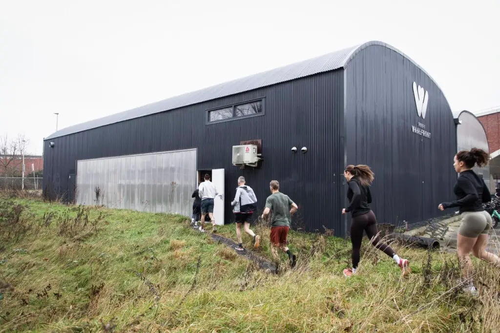 Leden lopen terug naar binnen bij de donkere hal van CrossFit Waalfront op het NYMA-terrein