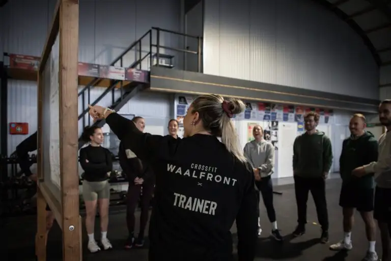 Trainer legt de oefeningen uit aan het whiteboard aan een groep tijdens de On-Ramp
