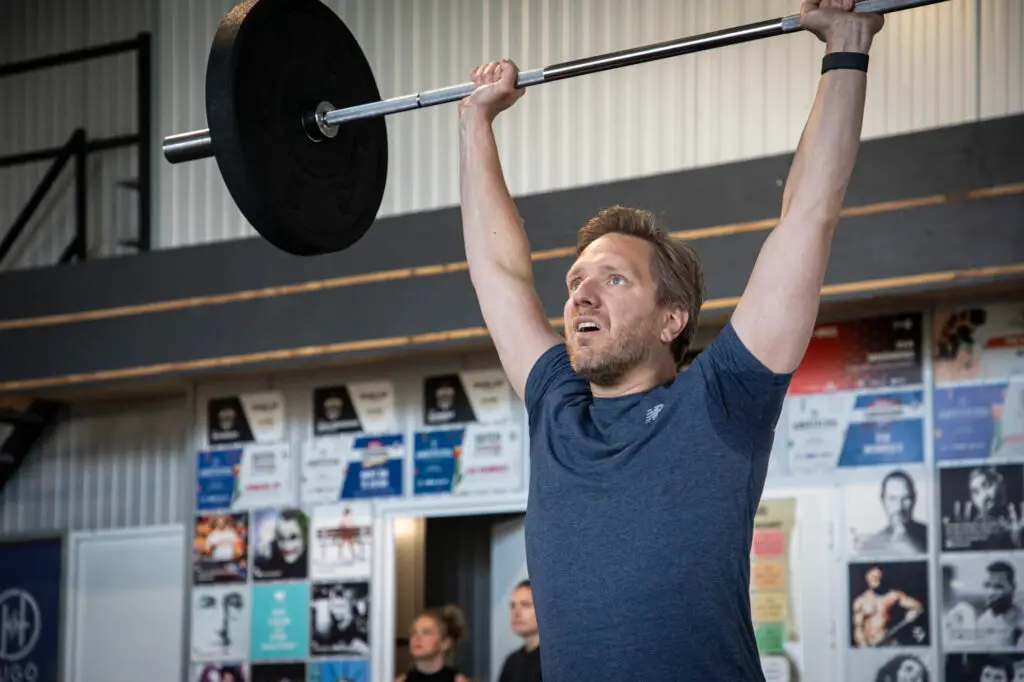 Lid drukt de barbell boven het hoofd tijdens de StrengthWOD