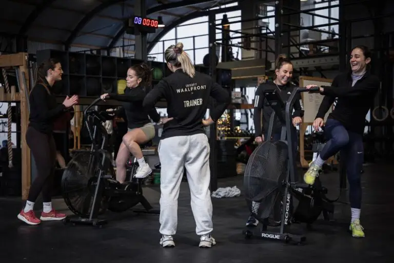 Trainer begeleidt de gezamenlijke warming-up bij de assault bikes
