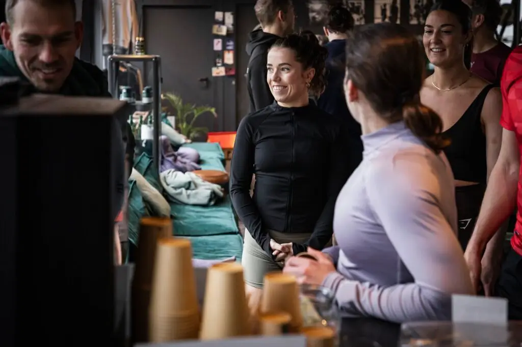 Leden praten na met koffie in de box, met yogamatten op de achtergrond